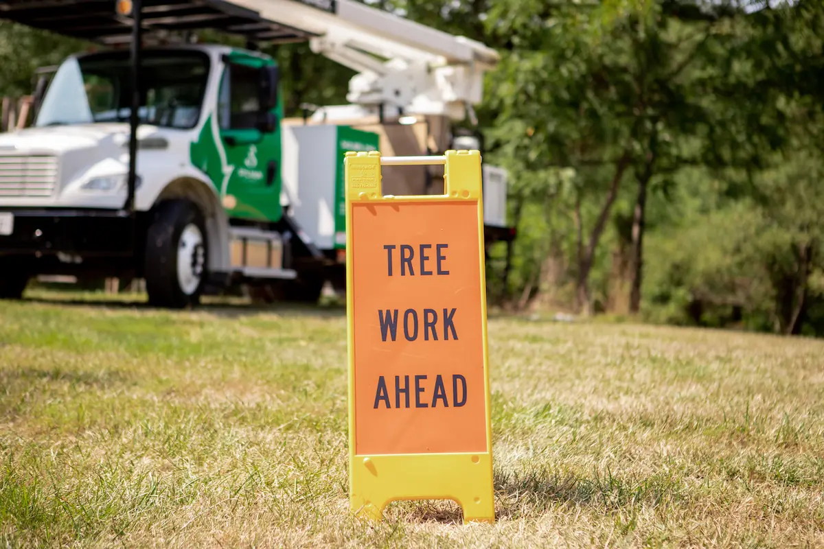 Tree work ahead safety sign set out in front of a Sylvan Scapes bucket truck at a job site